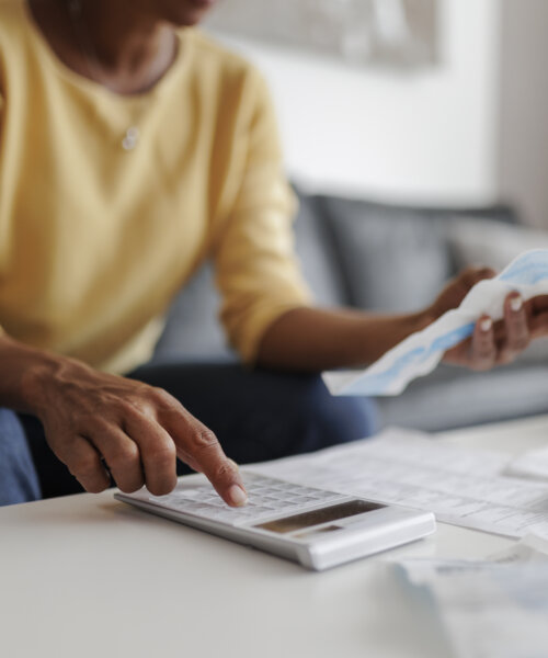 Adult woman using calculator and reviewing bills