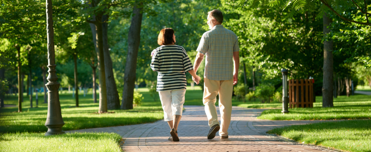 Couple holding hands in the park. Back view walking man and woman outdoors.