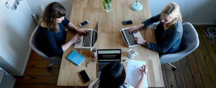 group of women on laptops sitting at a conference room table